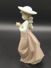 Perfil lateral de la figura de porcelana Nao Lladó, niña con sombrero y cesta de flores, pieza decorativa para el hogar.