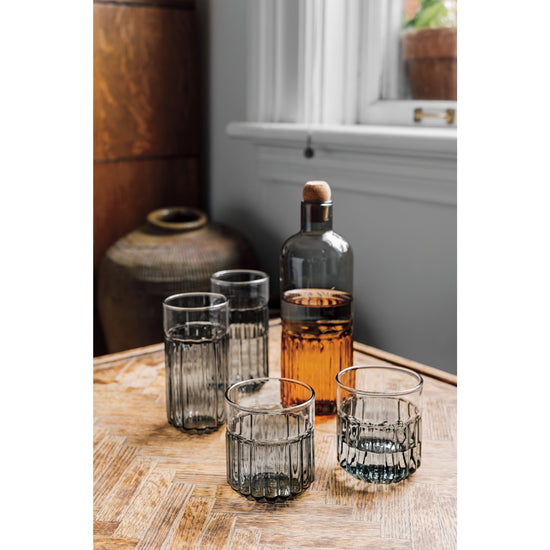 several grey drinking glass arranged on a table with a bottle