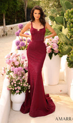 A woman in the Amarra Boned-Bodice Long Red Prom Dress 88796 stands outdoors beside large white planters filled with pink and purple flowers.